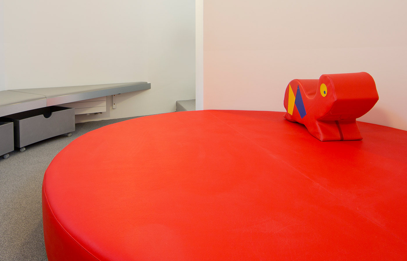 Prostor z velikim okroglim rdečim oblazinjenim počivališčem.