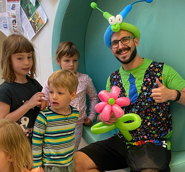 Zvedavi otroci ob nasmejanem čarodeju.