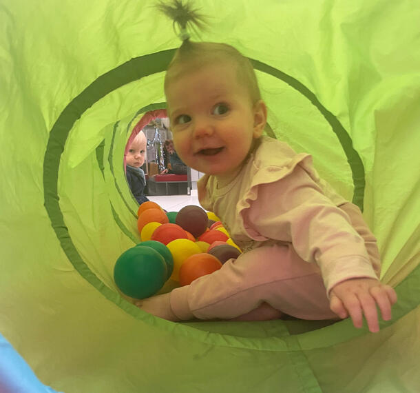 Dojenčica v igralnem tunelu z žogami.