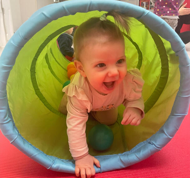 Smejoča dojenčica na robu igralnega tunela.