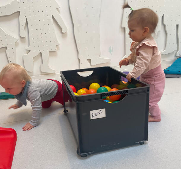 Dojenčka pred škatlo, polno žog.