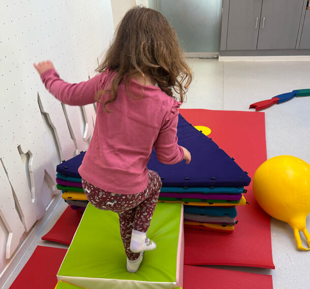Deklica med igranjem na blazinah v igralnici.