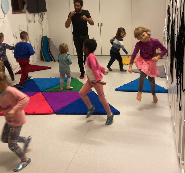 Otroci plešejo v igralnici ob spremljanju animatorja.
