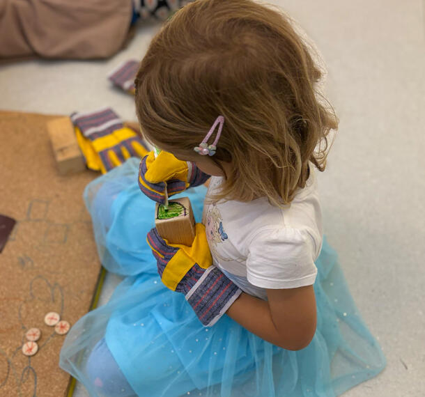 Deklica med risanjem na leseno kocko.