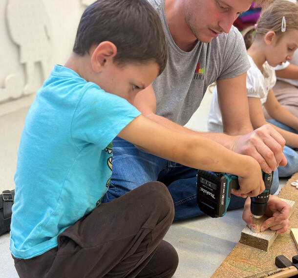 Deček z pri vrtanju luknje v les.