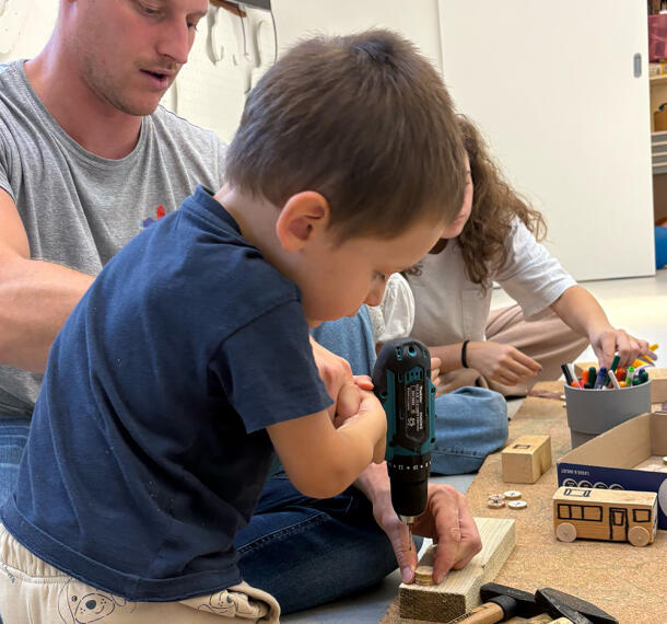 Deček z pri vrtanju luknje v les.