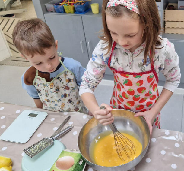 Deklica pri mešanju sestavin, deček opazuje.