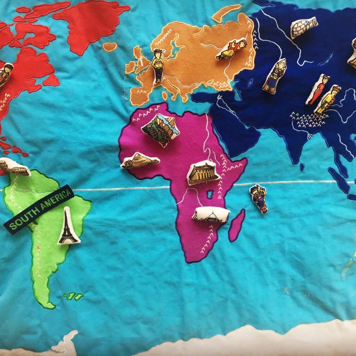 Svetovni zemljevid iz blaga s plišastimi znamenitostmi posameznih držav, poločenimi nanj.