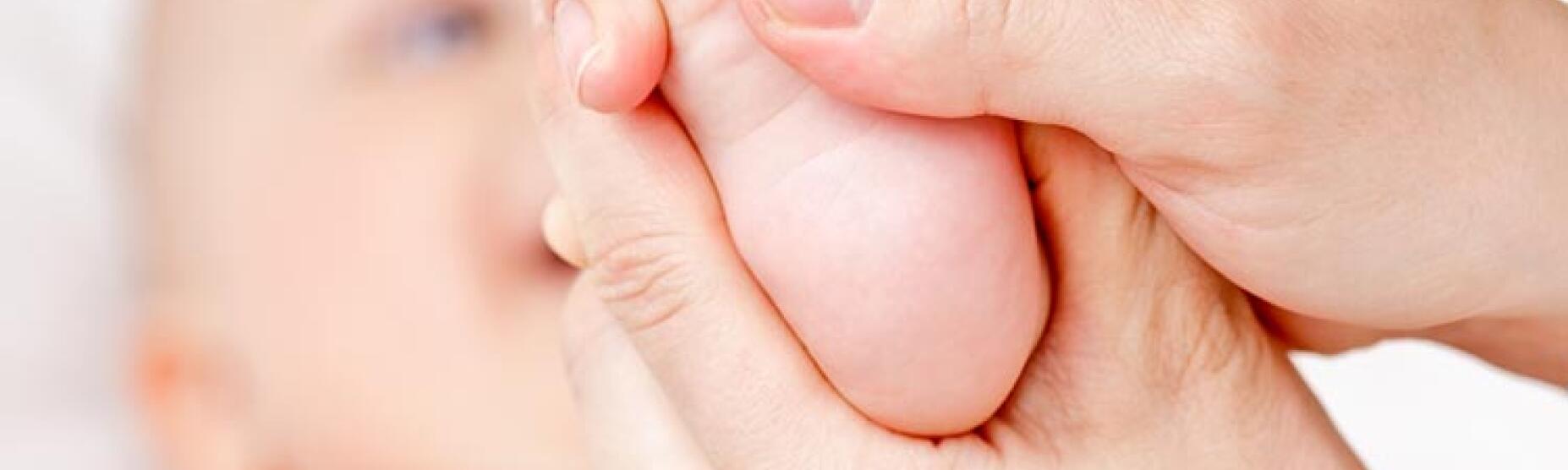 Vaditeljica dojenčku masira stopalo.