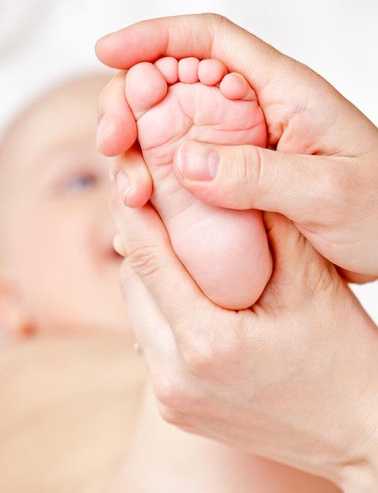 Vaditeljica dojenčku masira stopalo.