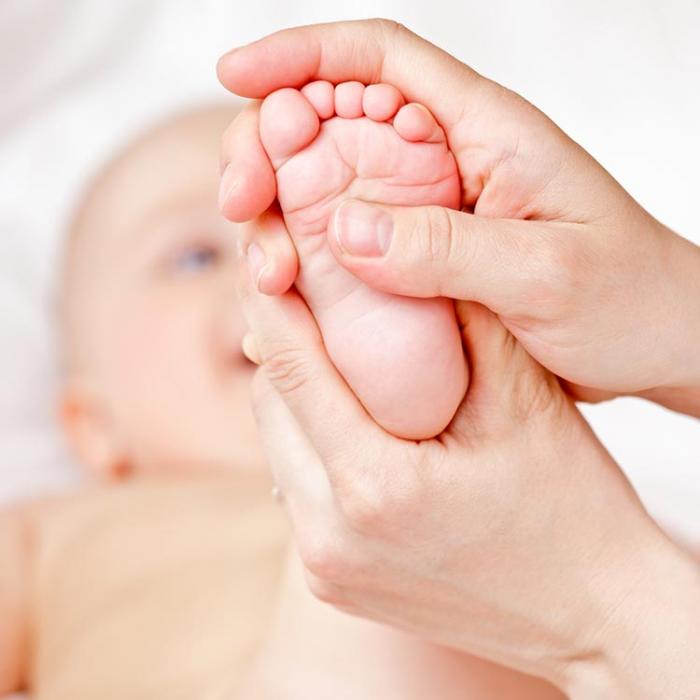 The instructor massages baby's foot.