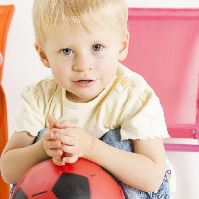 A boy leaning on a large ball.