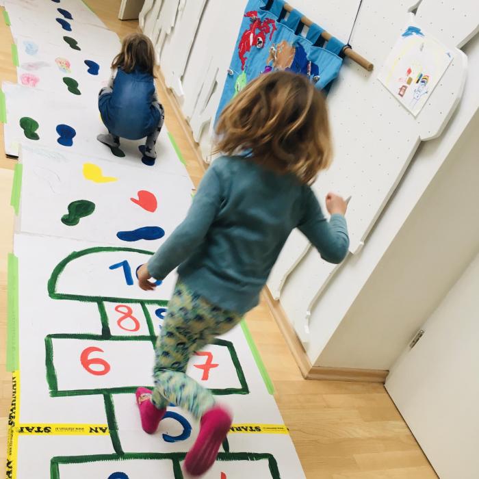 The girls playfully jumping on the floor markings.