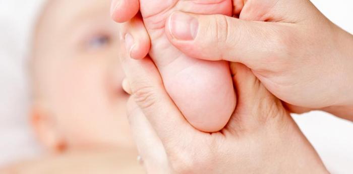 The instructor massages baby's foot.