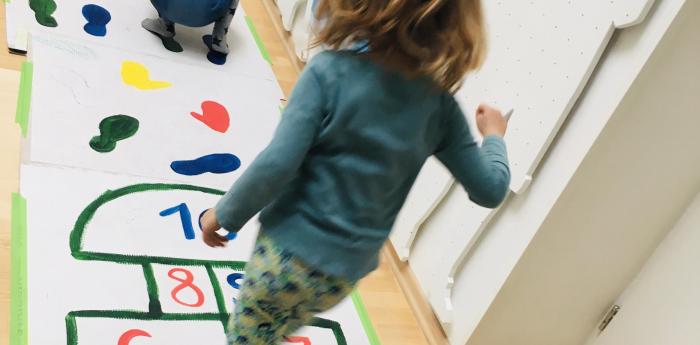 The girls playfully jumping on the floor markings.