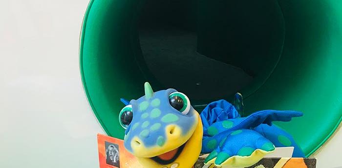 Plišasti dinozaver Dino ob branju slikanice.