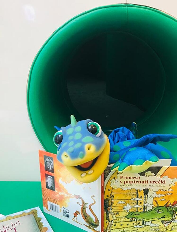 Plišasti dinozaver Dino ob branju slikanice.