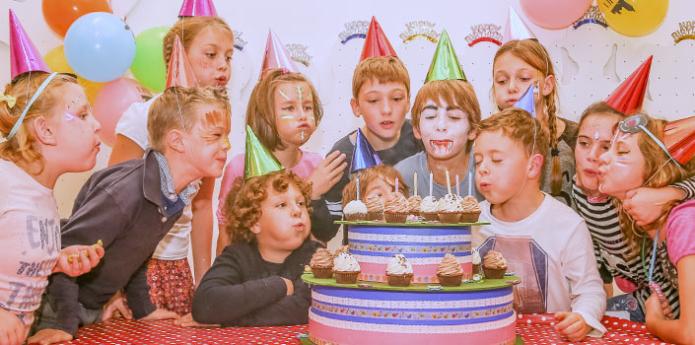 Razposajeni otroci ob torti na rojstnodnevni zabavi.