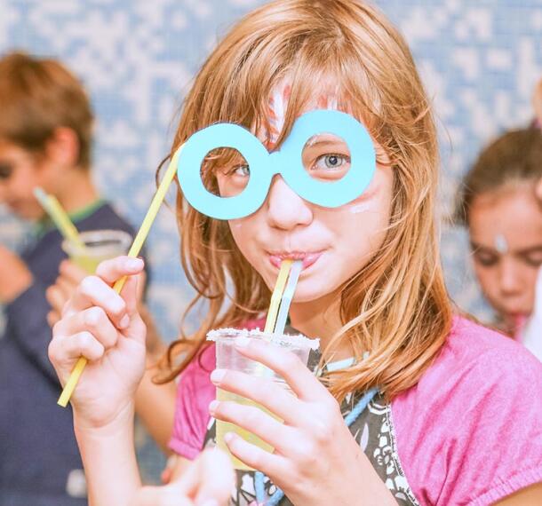 Razposajena deklica na zabavi s sokom v roki.