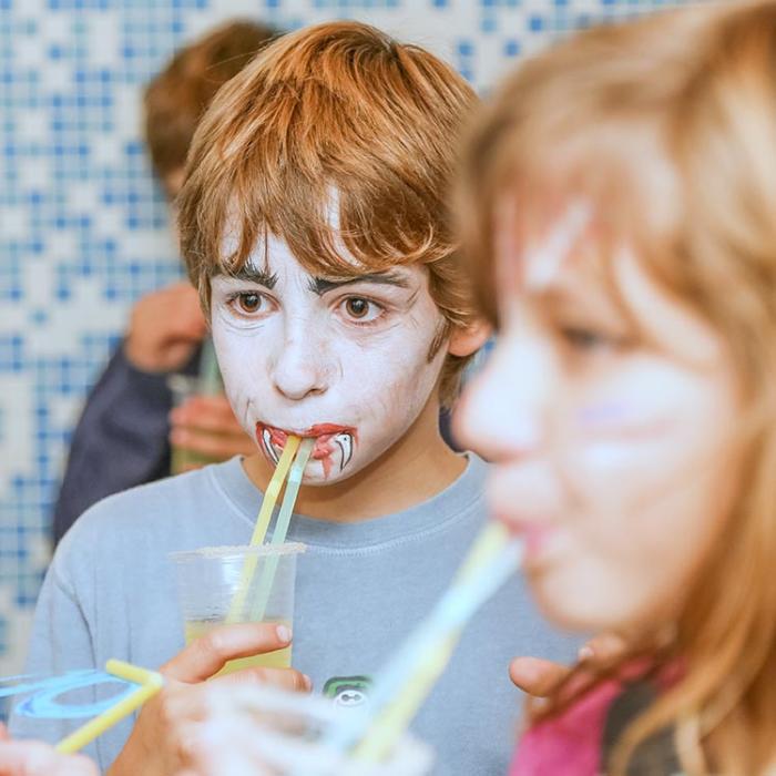 A boy at a party with juice in his hand.