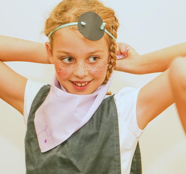 Mlada gusarka si popravlja gusarsko prevezo čez oči.