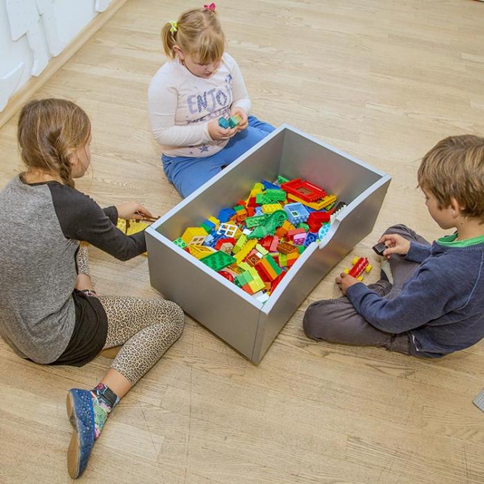 Otroci ob škatli z lego kockami.