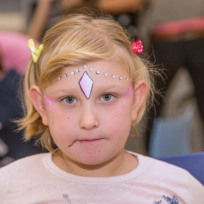 A girl from a birthday party, artfully painted on her face.