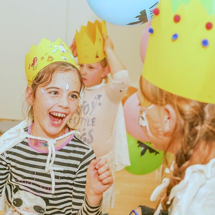 Exuberant girl with a paper crown on her head.