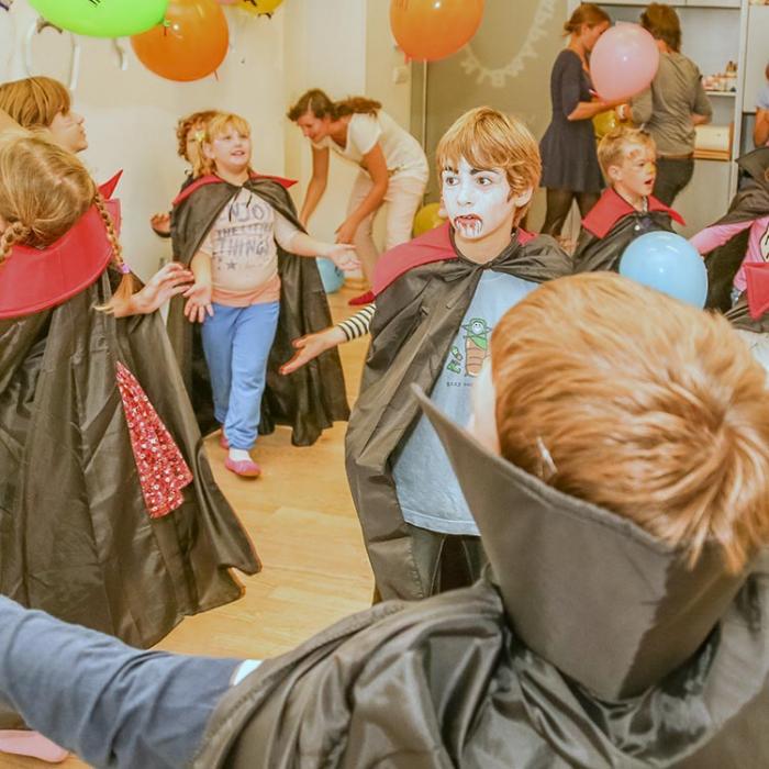 Kids having fun on the dance floor wearing vampire cloaks.