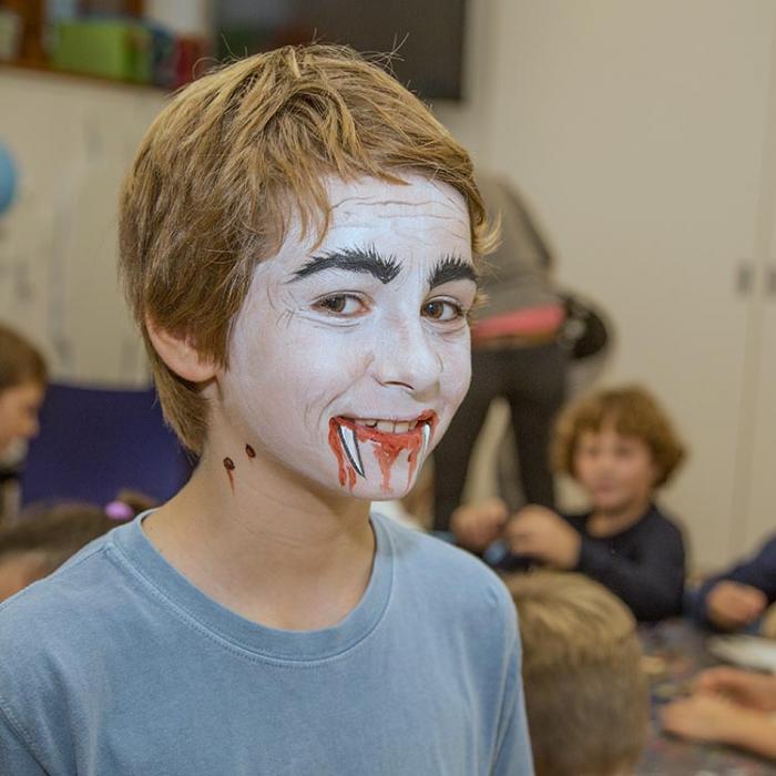 A boy with a vampire face painting.