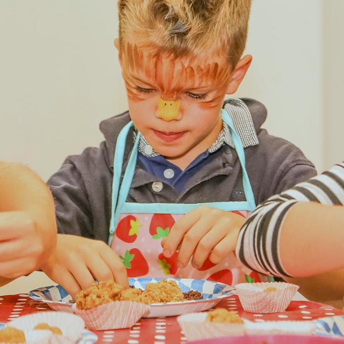 A boy with a painted face making sweets for his friends.