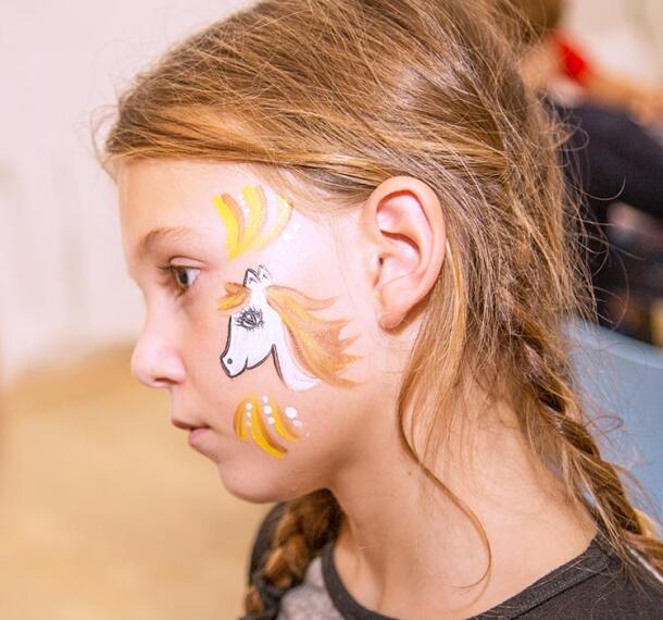 Deklica na zabavi z umetelno poslikanim obrazom.