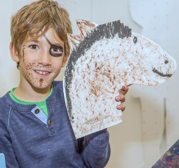 Deček z ročno izdelanim in pobarvanim kartonastim konjem.