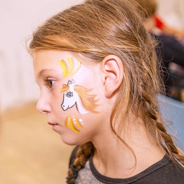 A girl at a party with an artfully painted face.