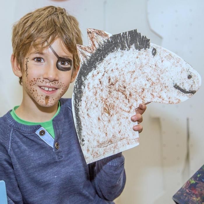 A boy with a handmade cardboard horse.