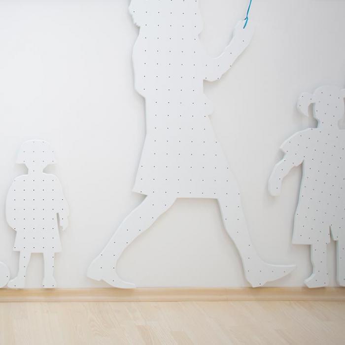 White wall with cut-out family silhouette attached to it in the interior playroom. The silhouettes depict mother and child.